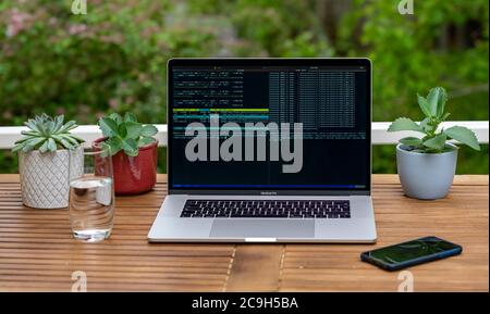 Home Office mit Laptop, Apple MacBook Pro mit iPhone X am Schreibtisch, mit offener Konsole während der Programmierung, Deutschland Stockfoto