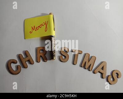 frohe Weihnachten Wort mit Holzbuchstaben Kunst auf Kreuztext Stift Papier Slip Konzept vorgestellt. Stockfoto