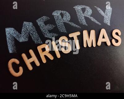 frohe Weihnachten Wort präsentiert mit Holzbuchstaben Kunst auf Kreidetafel Textkonzept. Stockfoto
