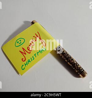 frohe Weihnachten Wort präsentiert mit Holzbuchstaben Kunst auf Stift Papier Slip Konzept. Stockfoto