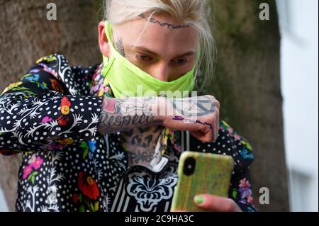 Köln, Deutschland. Juli 2020. Zur Eröffnung seiner Ausstellung 'Sturm' überprüft der Künstler Alexander Höller mit seinem Smartphone die Position des Wortes Sturm auf seiner Hand, bevor er sich tätowiert. Quelle: Henning Kaiser/dpa/Alamy Live News Stockfoto