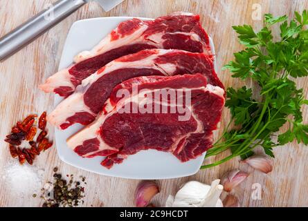 Zutaten zum Kochen. Rohbeef-Entrezitate mit frischer Petersilie, Zwiebel, Knoblauch und Gewürzen auf Holzoberfläche Stockfoto