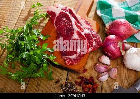 Zutaten zum Kochen. Rohbeef-Entrezitate mit frischer Petersilie, Zwiebel, Knoblauch und Gewürzen auf Holzoberfläche Stockfoto