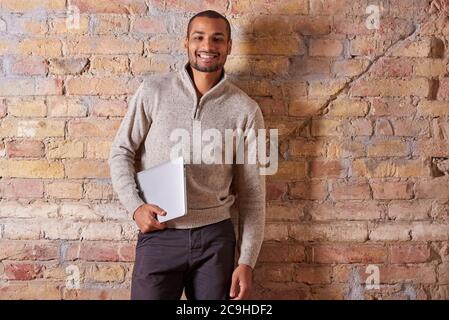 Ein hübscher junger Mann mit einem Laptop in einen Pullover. Stockfoto