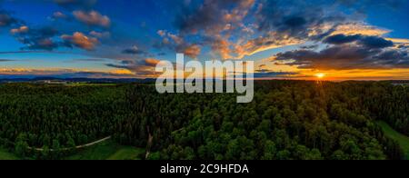 Toller Sonnenuntergang über einem Wald im Sommer, Panoramablick auf die Luft mit dramatischen Wolken. Stockfoto