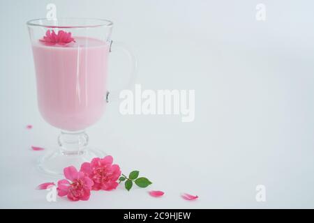 Rosenmondmilch für einen besseren Schlaf mit Kopierplatz. Ayurveda warmes Getränk verbraucht vor dem Bett. Schön im Falle von Schlaflosigkeit. Weißer Hintergrund, Nahaufnahme. Stockfoto