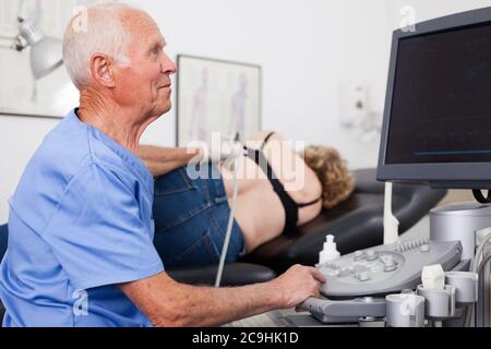 Senior Mann Arzt mit Ultraschall Gerät während untersucht reife Frau an den Nieren Stockfoto