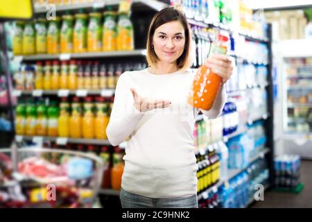 Hübsche junge Frau auf der Suche nach Getränken im Supermarkt Stockfoto