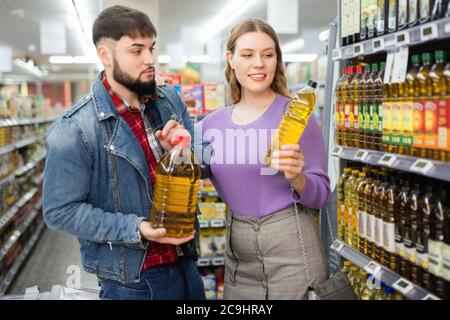 Lächelnd fröhlich positive Mädchen mit ihrem bärtigen Freund, die Einkäufe im Supermarkt, auf der Suche nach Pflanzenöl Stockfoto