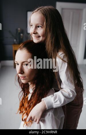 Yong und Erwachsene Schwestern umarmen sich im Loft, die Freundschaft, Vertrauen, Ähnlichkeit repräsentieren Stockfoto
