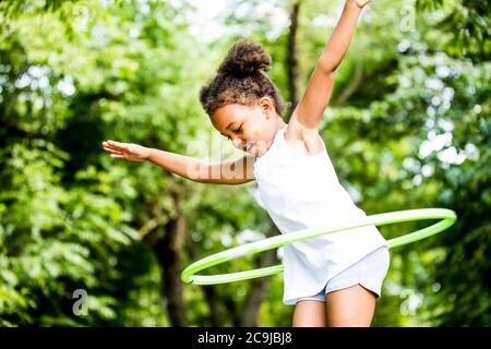 Mädchen spielt mit Hula Hoop im Park, lächelnd. Stockfoto