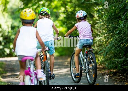 Kinder tragen Helme und Radfahren im Park. Stockfoto