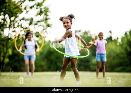 Mädchen spielen mit Hula Hoops im Park. Stockfoto