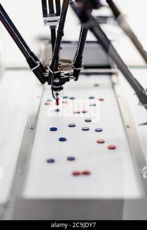 Roboterhandhabmaschine für die Pharmaindustrie. Roboterarm erkennt und kommissioniert nur Produkte, die den gewünschten Eigenschaften entsprechen. Stockfoto