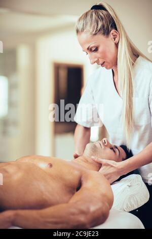 Sportmassage. Physiotherapeut massiert Mann den Hals. Stockfoto