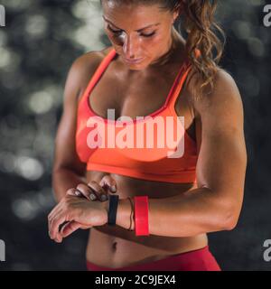 Sport im Freien. Weibliche Athletin, die ihr Fitnessband verwendet, um ihre Aktivitäten zu verfolgen. Stockfoto