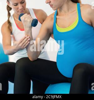 Schwangere Frau macht einfache Übung mit Lehrer. Stockfoto