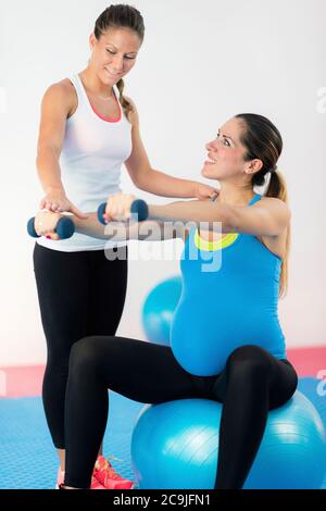 Gesunde Lebensweise in der Schwangerschaft. Schwangere Frau Aufrechterhaltung eines gesunden Lebensstils, Training mit Fitness-Trainer. Stockfoto
