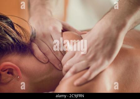 Nahaufnahme einer jungen Frau mit geölter Haut mit einer entspannenden Schultermassage. Stockfoto