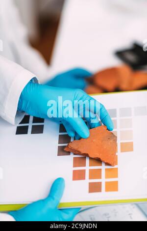 Junger Archäologe vergleicht Keramik Farben mit Farbkarte Schema im Labor. Stockfoto