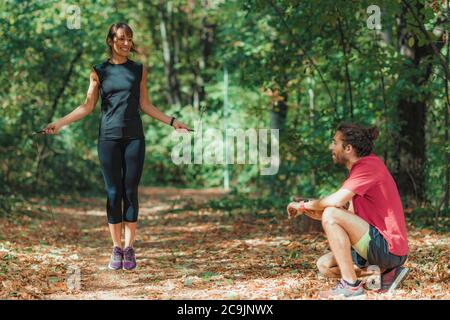 Freunde trainieren im Freien. Frau springt an einem Seil. Stockfoto