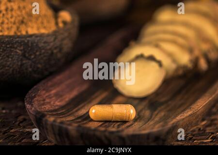 Ingwer Kräuterergänzung Kapsel, Ingwer gemahlenes Gewürzpulver und frisch geschnittene Wurzel auf dem Tisch. Kräutermedizin gegen Entzündungen. Stockfoto