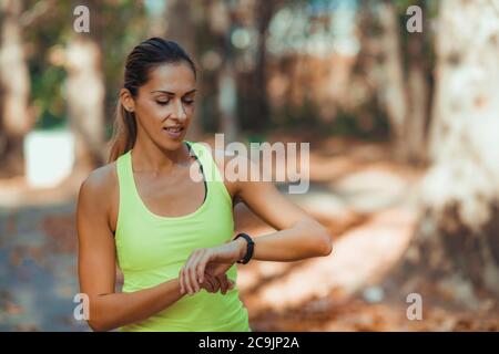 Frau überprüft den Fortschritt auf der Smart Watch nach dem Training im Freien. Stockfoto