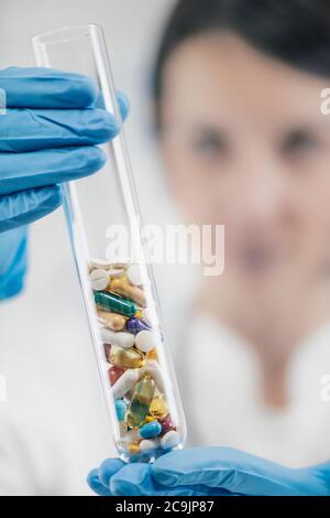 Pharmazeutische Forschung. Doctor's Hand hält Labor Glas Reagenzglas mit bunten Pillen gefüllt. Stockfoto