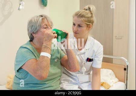 Geriatrische Krankenhausabteilung. Krankenschwester, die einem verwirrten Patienten auf der geriatrischen Abteilung eines Krankenhauses hilft. Stockfoto