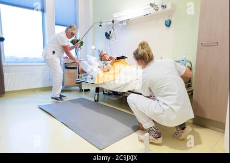 Geriatrische Krankenhausabteilung. Krankenschwestern, die einem verwirrten Patienten auf der geriatrischen Abteilung eines Krankenhauses helfen. Stockfoto