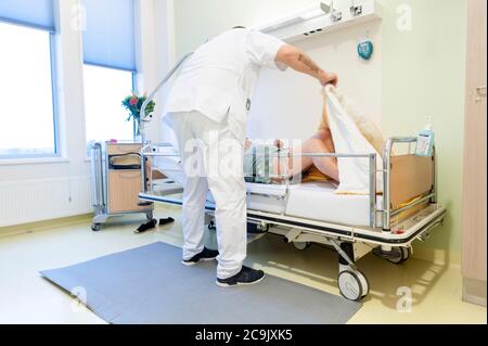 Geriatrische Krankenhausabteilung. Krankenschwester, die einem verwirrten Patienten auf der geriatrischen Abteilung eines Krankenhauses hilft. Stockfoto