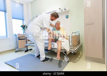 Geriatrische Krankenhausabteilung. Krankenschwester, die einem verwirrten Patienten auf der geriatrischen Abteilung eines Krankenhauses hilft. Stockfoto