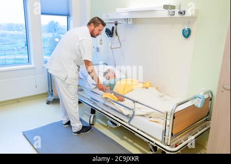 Geriatrische Krankenhausabteilung. Krankenschwester, die einem verwirrten Patienten auf der geriatrischen Abteilung eines Krankenhauses hilft. Stockfoto