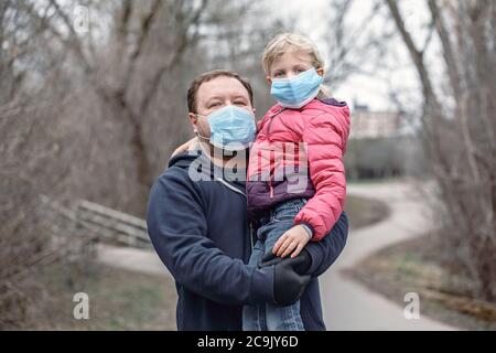 Kaukasischen Vater mit Kind Mädchen tragen sanitäre Gesichtsmasken im Freien. Familie Vater und Tochter schützen sich vor gefährlichen Ausbreitung des Virus. Stockfoto