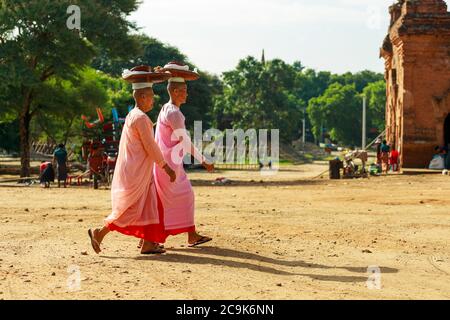 Bagan/Myanmar-4. Oktober 2019: Zwei burmesische Nonnen mittleren Alters legten einen Korb auf ihre Köpfe, um Verdienste im Tempel zu verdienen. Stockfoto