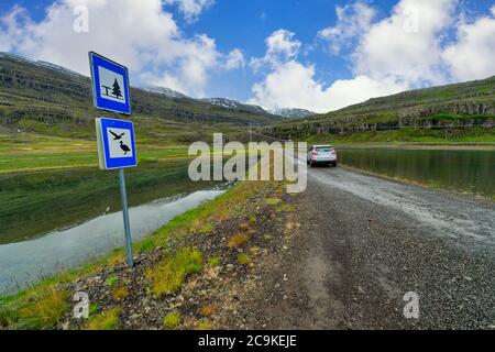 Autos geparkt auf einem Feldweg in der Mitte der großen Natur Panoramablick auf das Tal und den See im Sommer der Landschaft in Island. Stockfoto