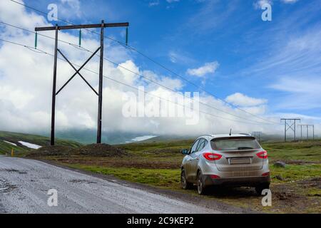 Silber Bronze SUV in voll schlampigen Zustand Parken Sie das Auto auf der Seite einer Landstraße in Island. Der blaue Himmel und schöne Wolken im Konzept der Stockfoto