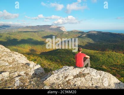 Mann sitzt am Rande des Klippenbergs. Konzeptuelle Szene. Stockfoto