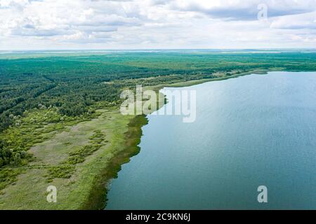 Sommer Landschaft mit blauem See und grünen Wald unter bewölktem Himmel. Luftaufnahmen mit Drohne Stockfoto