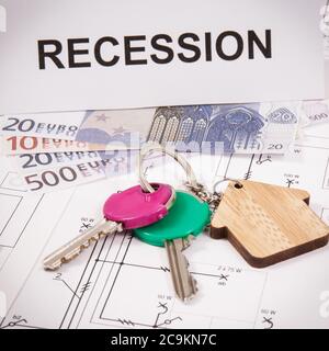 Schlüssel mit Home Form, Währungen Euro und Inschrift Rezession auf elektrischen Diagrammen des Hauses. Konzept der Immobilienkrise Stockfoto