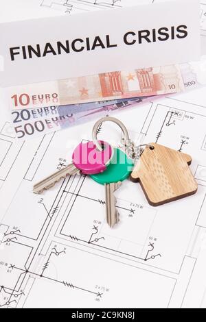 Schlüssel mit Hausform, Währungen Euro und Inschrift Finanzkrise auf elektrischen Bauzeichnungen. Konzept der Immobilienkrise Stockfoto