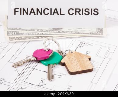 Schlüssel mit Home Form, Währungen Dollar und Inschrift Finanzkrise auf elektrischen Bauzeichnungen. Konzept der Immobilienkrise Stockfoto