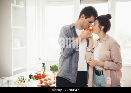 Schöne kaukasische Paar essen Orange zusammen in der Küche während der Zubereitung von Essen Stockfoto