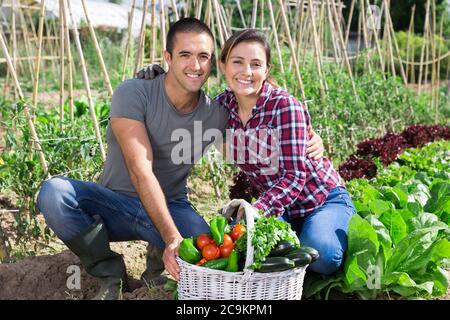 Portrait von glücklichen liebenden biracial Familie Paar stolz auf die Ernte von Gemüse in ihrem Garten angebaut Stockfoto
