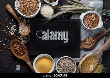 Verschiedene Arten von Getreide in Schüsseln auf schwarzem Hintergrund. Gesunde Ernährung Essen. Draufsicht Stockfoto