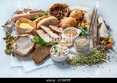 Verschiedene Arten von kohlenhydratreichen Lebensmitteln. Auswahl der guten Quellen der Kohlenhydrate auf grauem Hintergrund. Stockfoto