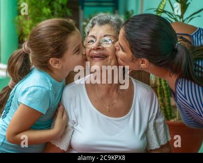 Ein Mädchen und eine junge Frau, die eine alte Frau küssen Stockfoto