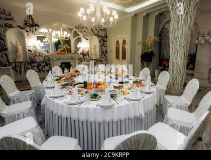 Wunderschön dekorierter festlicher Tisch mit Tellern und Gläsern und einem Blumenstrauß in einem Restaurant Stockfoto