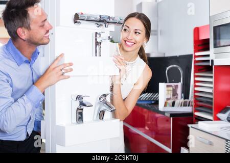 Junge liebevolle Paar aus hinter Zähler mit Mischbatterie spähen Stockfoto