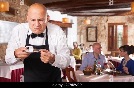 Männliche Kellner demonstriert seine umgekippt mit kleinen Tipps vom Restaurant Besucher Stockfoto